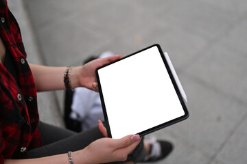 Cropped image of the hand using a white blank screen digital tablet in the park.