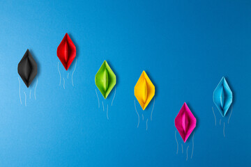 paper boat concept. boats in various colors  in business competiton on blue background. leader...