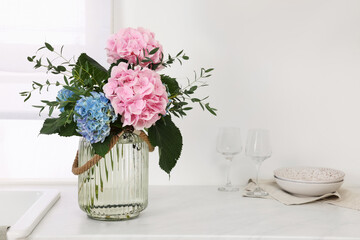 Beautiful hortensia flowers in vase on kitchen counter. Space for text