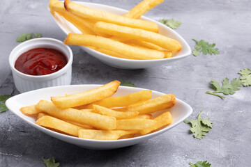 French fries with ketchup in white ceramic cup on gray background