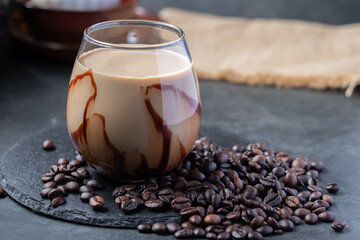 Coffee mixed with brown sugar in a clear glass and coffee beans.