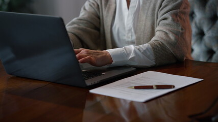 Senior business woman using laptop at home workplace. senior woman hands