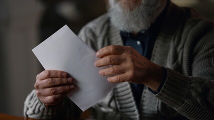 Happy old gentleman receiving letter in cabinet. Glad man opening envelope house