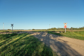 Fototapeta na wymiar A dirt road leading to a stop sign at the railway crossing in rural Saskatchewan, Canada.