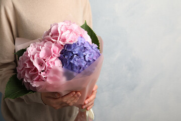 Woman with bouquet of beautiful hortensia flowers on color background, closeup. Space for text