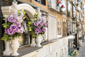 Graves in concrete niches with bouquets of flowers in the wall of an old cemetery.