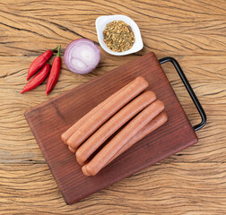 Thin pork sausage over wooden board with seasonings