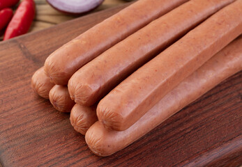 Thin pork sausage over wooden board with seasonings