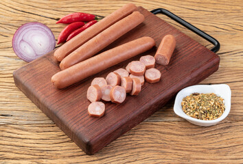 Thin pork sausage over wooden board with seasonings
