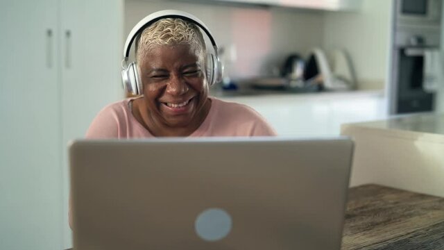 Happy senior latin woman having fun doing video call using laptop at home - Technology and smart working concept
