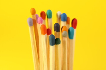 Matches with colorful heads on yellow background, closeup