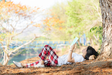 A girl enjoying reading under a tree with a relaxing atmosphere like in an outdoor park.
