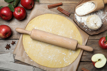 Dough for apple pie and ingredients on wooden table, flat lay