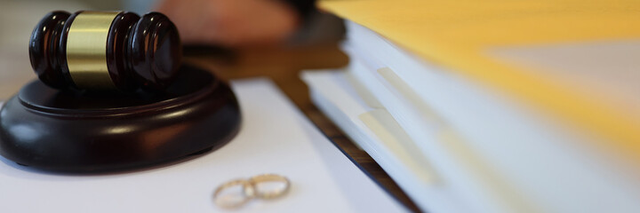 Wedding rings and wooden judge gavel lie on table