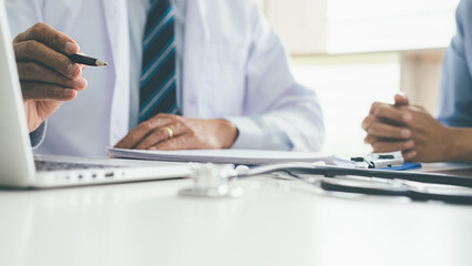 Patient listening intently to a male doctor explaining patient symptoms or asking a question as they discuss paperwork together in a consultation