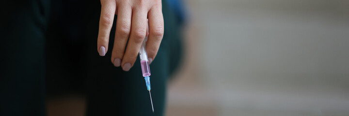 In female hand syringe with needle closeup