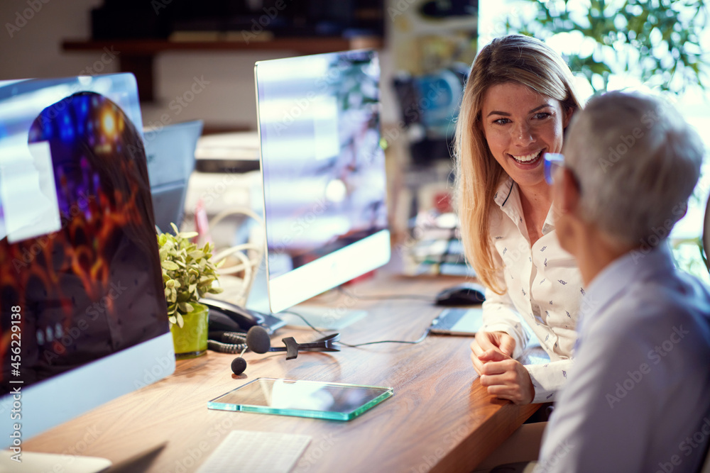 Wall mural a young business woman enjoys working with her elderly female colleague at workplace. business, offi