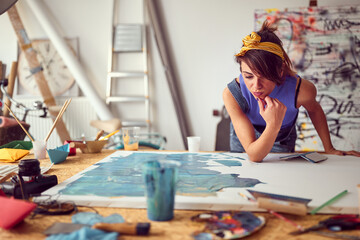 A young female artist brainstorming on a new painting she is working on in the studio. Art, painting, studio