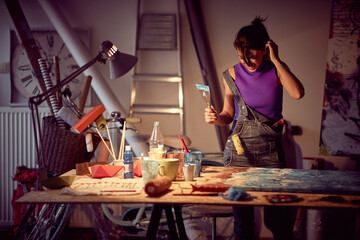 A young female artist in a creative process of making a new painting in the studio. Art, painting, studio