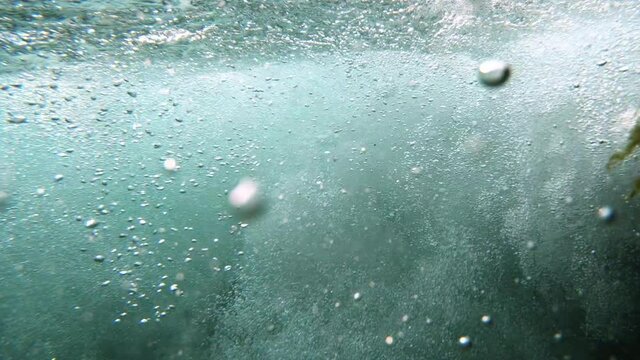 Underwater surge of bubbles in current downstream of small waterfall flowing in the Utah wilderness.