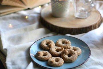 Plate with cookies, open book, lit candles and fairy lights. Hygge at home. Selective focus.