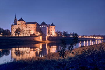 Obraz premium Das beleuchtete Schloss Hartenfels am Ufer der Elbe in Torgau.