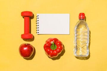 Fitness concept. Collection of fresh fruits with dumbells and water bottle on yellow background.