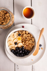 Bowl with healthy granola with honey, banana and berries for breakfast