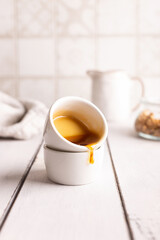 Honey is poured out of a small cup