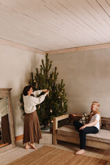 Happy lovers a man and a woman in cozy sweaters embrace spend time together celebrate Christmas relaxing on the sofa by the Christmas tree in the holidays in the interior in the style of eco friendly