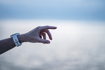 Woman's hand with a white watch points to something in the distance. Hand pointer