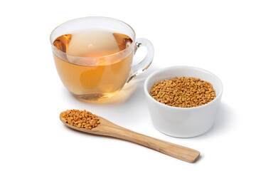 Glass cup with Fenugreek tea and a spoon and bowl with Fenugreek  seeds isolated on white background 