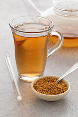 Fototapeta premium Glass cup with fresh Fenugreek tea and a bowl with Fenugreek seeds 