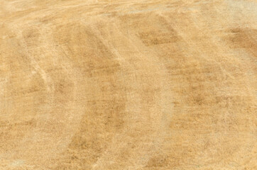 Texture from a field of golden grass mowed and the arc-shaped dark and light stripes