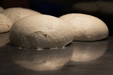 The uncooked round buns of dough are placed on a metal tray. Hamburger bun dough