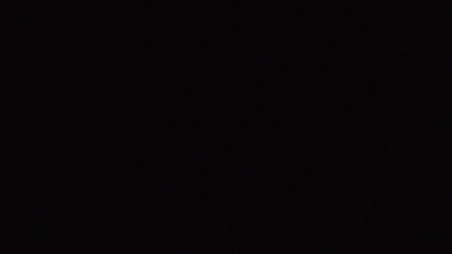 Footage of fast train passing by at night. Way locomotive and wagons, going nightly in dark. Blurry yellow windows, lights flash as the train goes by in the darkness.