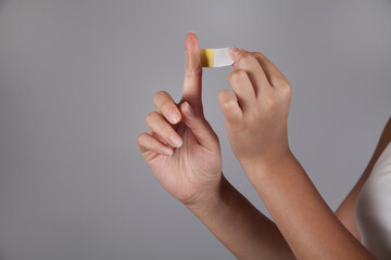 Woman putting adhesive bandage on finger.