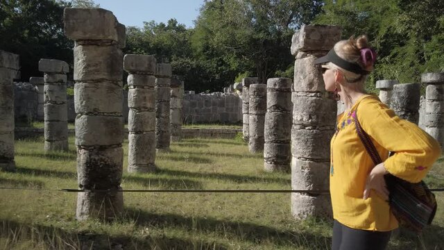 Mature blond woman walks among the ruins at Chichen Itza historical park in Yucatan, Mexico.