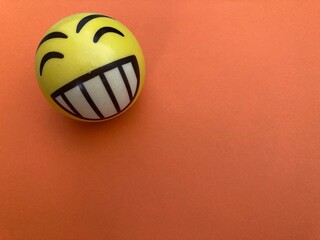 Pelota happy face amarillo sobre fondo naranja