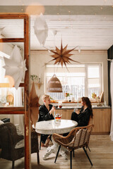 Married man and woman in love in pajamas having breakfast drinking tea sitting at the dining table in the kitchen in an eco style interior during the winter holidays in a cozy country house