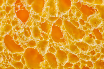 Close-up of the pores of a yellow sponge. A sponge for cleansing the skin after makeup or cosmetic...