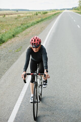 Fototapeta na wymiar Young woman in helmet riding on a bike on a road during sports competition