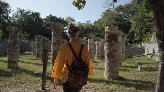 Mature blond woman walks among the ruins at Chichen Itza historical park in Yucatan, Mexico.