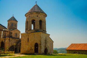 Fototapeta na wymiar KUTAISI, GEORGIA: View of the old stone Bell Tower in the Orthodox monastery of Gelati on a sunny summer day. UNESCO.