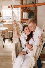 Happy lovers a man and a woman embrace, relax together and spend time in a cozy comfortable country house in eco-friendly style during the winter holidays, selective focus