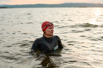 Female swimmer in swimsuit swimming in the lake during sunset outdoors