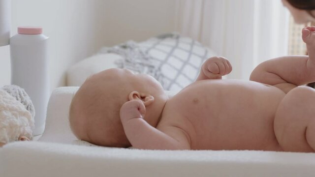 mother changing baby diaper at home caring for happy newborn infant loving mom cleaning childs nappy moisturizing skin enjoying motherhood childcare