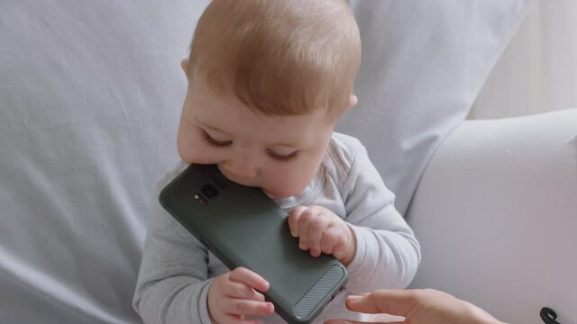 funny baby playing with smartphone toddler looking curious at phone infant learning using mobile technology at home