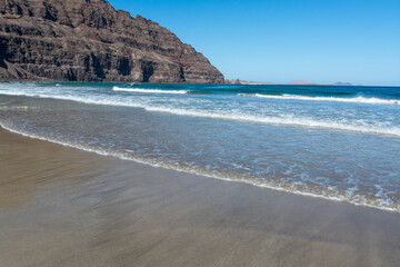 Black lava rocks and water waves of Atlantic ocean, nature landscape on Lanzarote, Canary islands, Spain