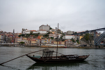 Porto, Portugal, October 31,2020. View from Vila Nova de Gaia on port makers boats and colorful old houses on hill in old part of city. Embankment of Douro river in rainy day